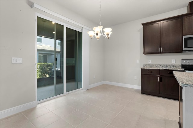 kitchen featuring decorative light fixtures, a chandelier, light stone counters, dark brown cabinetry, and stainless steel appliances