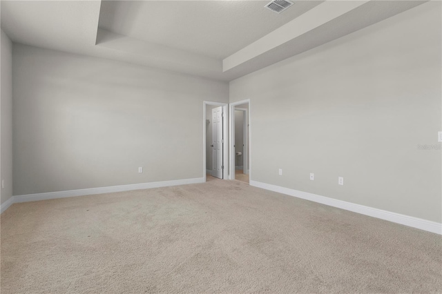 carpeted empty room featuring a raised ceiling