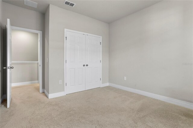 unfurnished bedroom with light colored carpet and a closet