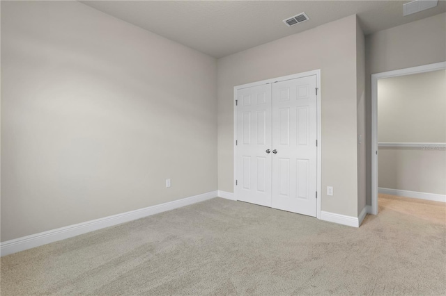 unfurnished bedroom featuring light carpet and a closet