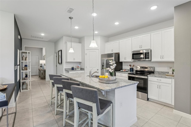 kitchen featuring appliances with stainless steel finishes, white cabinets, and an island with sink