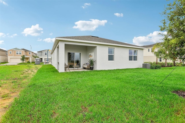 rear view of property featuring a garage, a patio area, a lawn, and central air condition unit