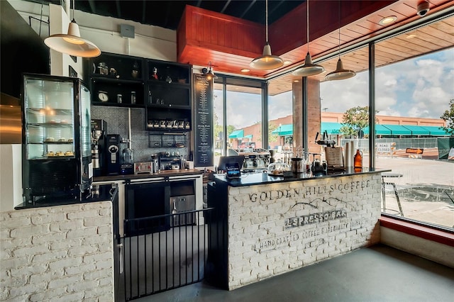 bar featuring pendant lighting, a wealth of natural light, and concrete flooring