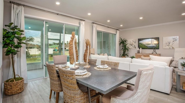 dining area with a wealth of natural light, crown molding, and light wood-type flooring