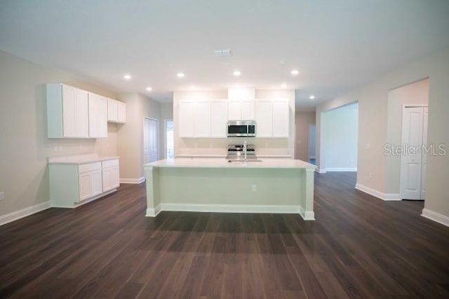 kitchen featuring white cabinetry, dark hardwood / wood-style flooring, stainless steel appliances, and an island with sink