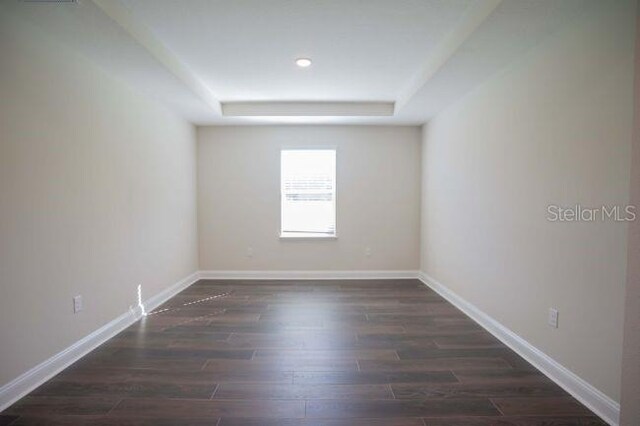 empty room featuring dark hardwood / wood-style floors and a tray ceiling