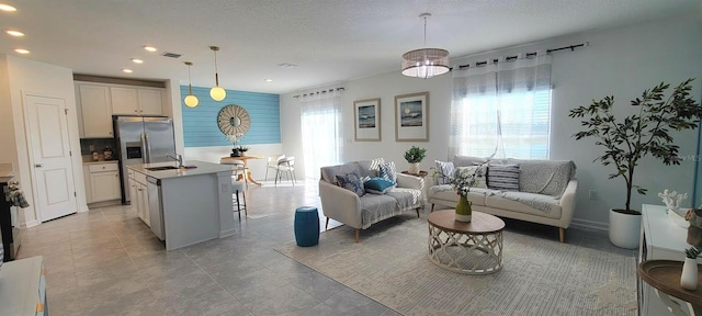 living room with a textured ceiling, a wealth of natural light, and sink