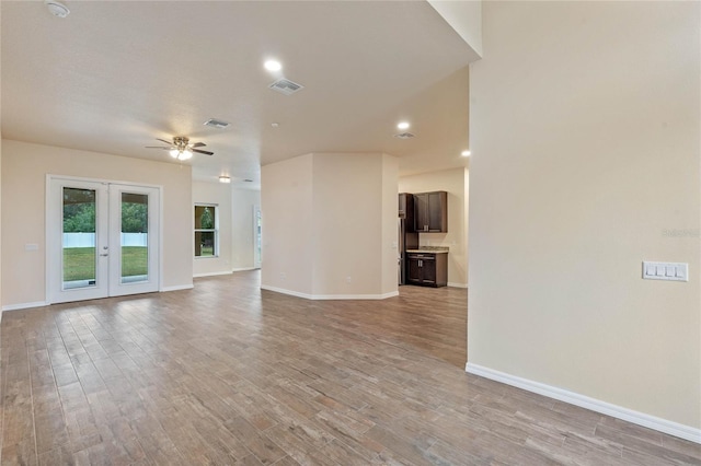 unfurnished living room with ceiling fan, light wood-type flooring, and french doors