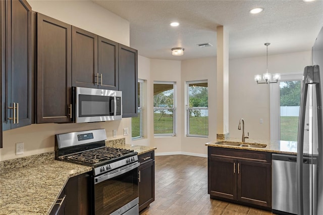 kitchen featuring sink, dark brown cabinets, stainless steel appliances, a textured ceiling, and light wood-type flooring