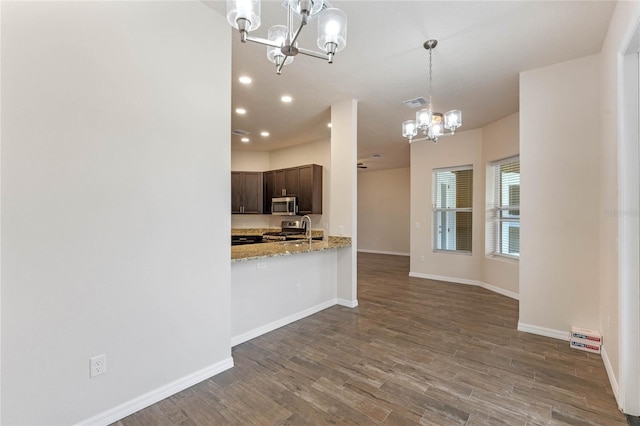 kitchen featuring a chandelier, hardwood / wood-style flooring, dark brown cabinetry, kitchen peninsula, and stainless steel appliances