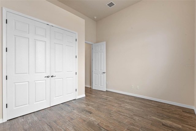 unfurnished bedroom with dark wood-type flooring and a closet