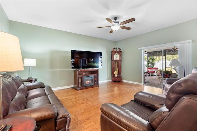 living room with ceiling fan, light wood-type flooring, and a fireplace