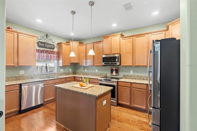 kitchen featuring sink, light stone counters, a kitchen island, light hardwood / wood-style floors, and stainless steel appliances