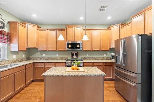 kitchen featuring light stone countertops, light hardwood / wood-style floors, a kitchen island, decorative light fixtures, and stainless steel appliances