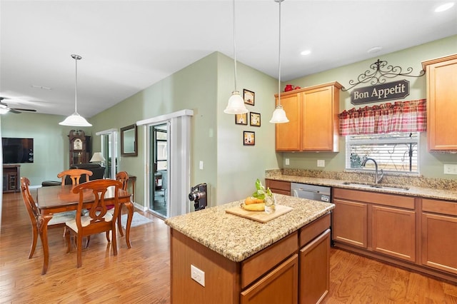 kitchen with decorative light fixtures, sink, a center island, and light wood-type flooring