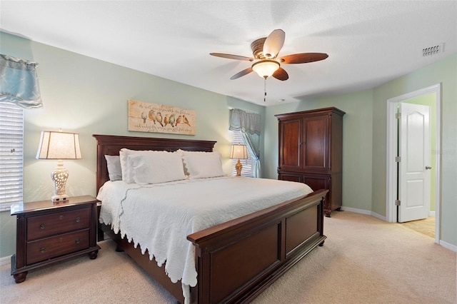 carpeted bedroom with ceiling fan, multiple windows, and ensuite bathroom