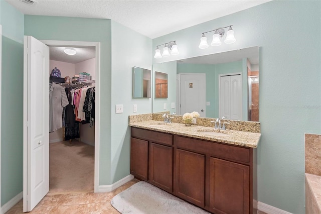 bathroom featuring a textured ceiling, tile patterned floors, and vanity