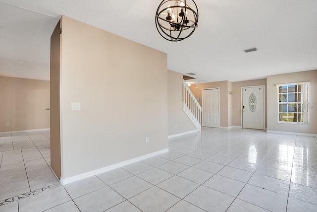 tiled empty room featuring a notable chandelier and a textured ceiling