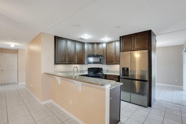 kitchen featuring black appliances, light tile patterned floors, a kitchen bar, and kitchen peninsula