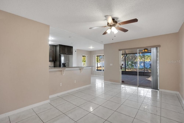 unfurnished room featuring a textured ceiling, ceiling fan, and light tile patterned flooring