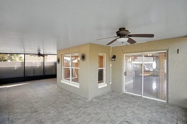 unfurnished sunroom featuring ceiling fan and a healthy amount of sunlight