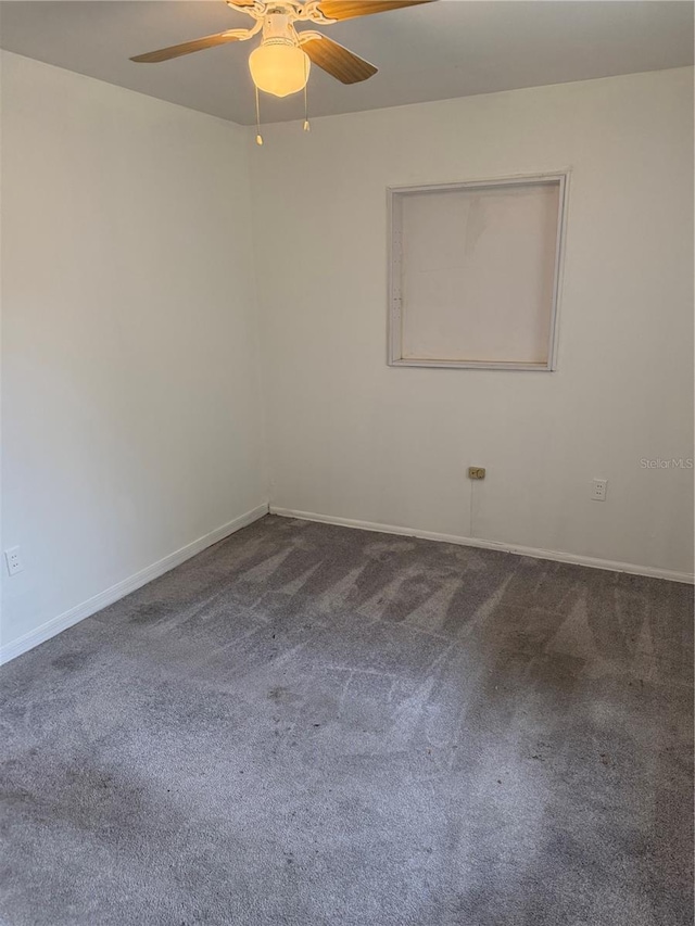 empty room featuring dark colored carpet, ceiling fan, and baseboards