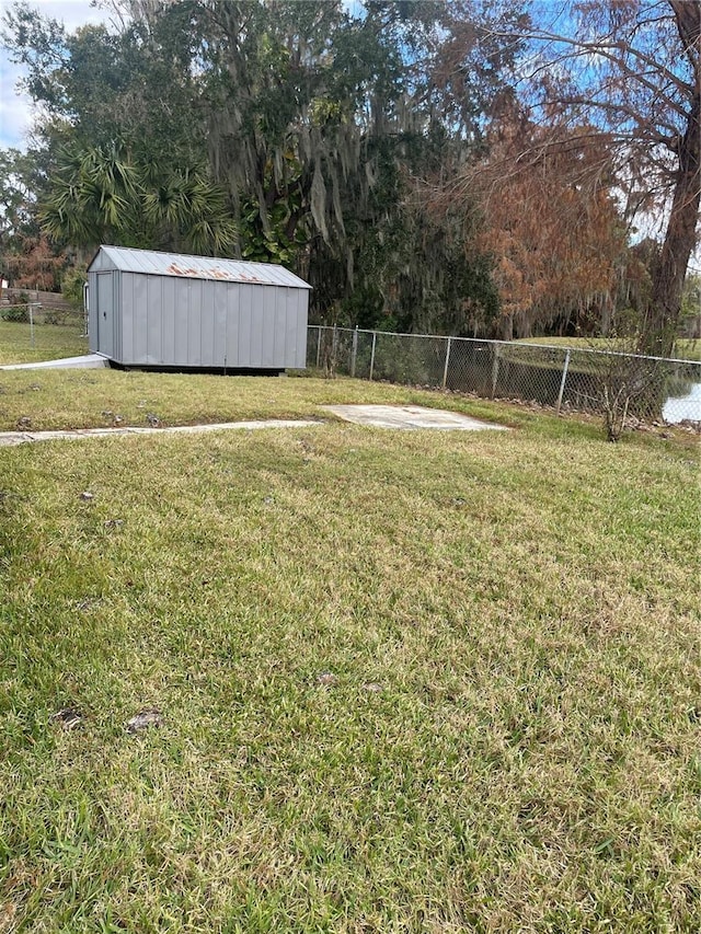 view of yard featuring a shed, a fenced backyard, and an outbuilding