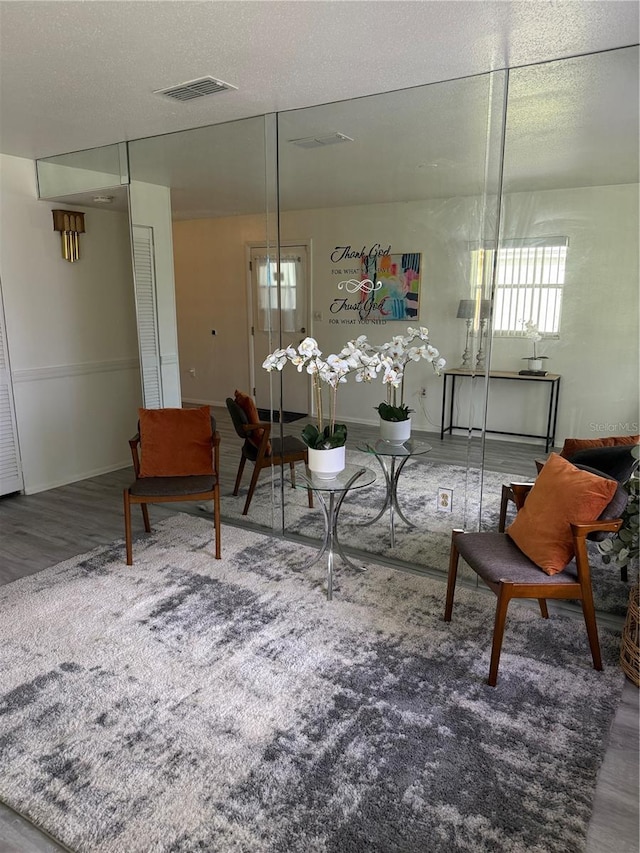 living area with a healthy amount of sunlight, a textured ceiling, visible vents, and wood finished floors