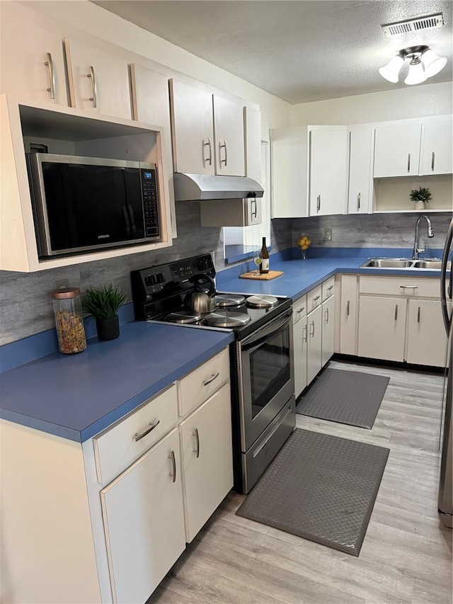 kitchen with visible vents, electric range, white cabinets, a sink, and under cabinet range hood