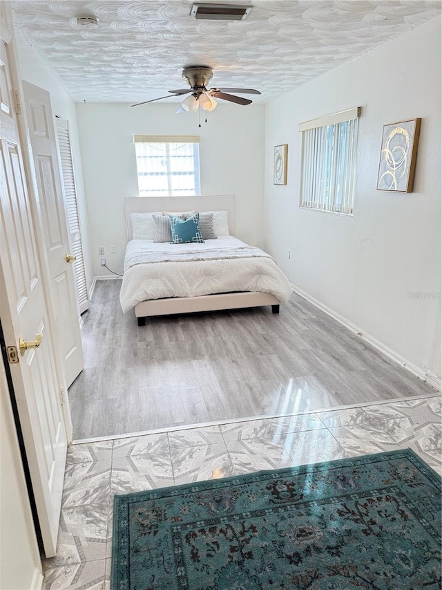 bedroom featuring a textured ceiling, visible vents, light wood-style flooring, and baseboards