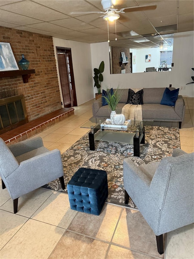 tiled living area with a paneled ceiling, a brick fireplace, and brick wall