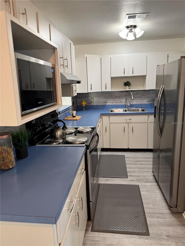 kitchen featuring stainless steel appliances, visible vents, white cabinets, a sink, and under cabinet range hood