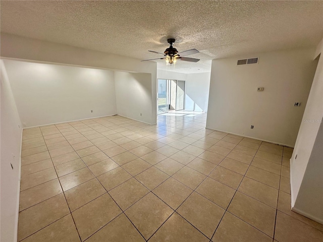 tiled empty room with ceiling fan and a textured ceiling