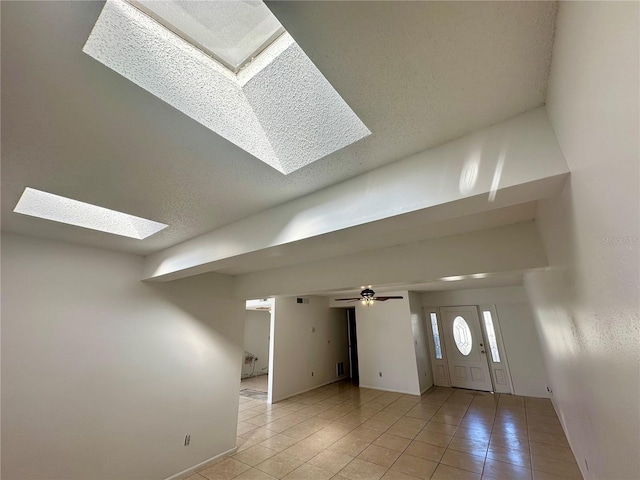 entryway featuring ceiling fan, light tile patterned floors, and a skylight