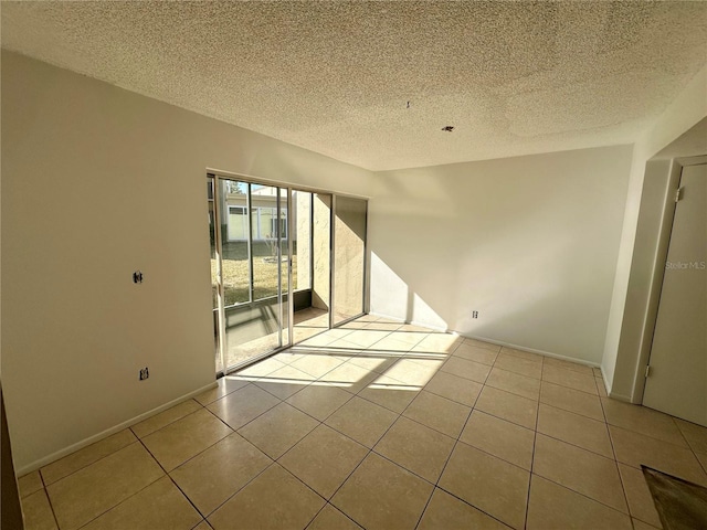 spare room with light tile patterned flooring and a textured ceiling