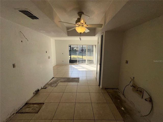 hall featuring light tile patterned flooring and a raised ceiling