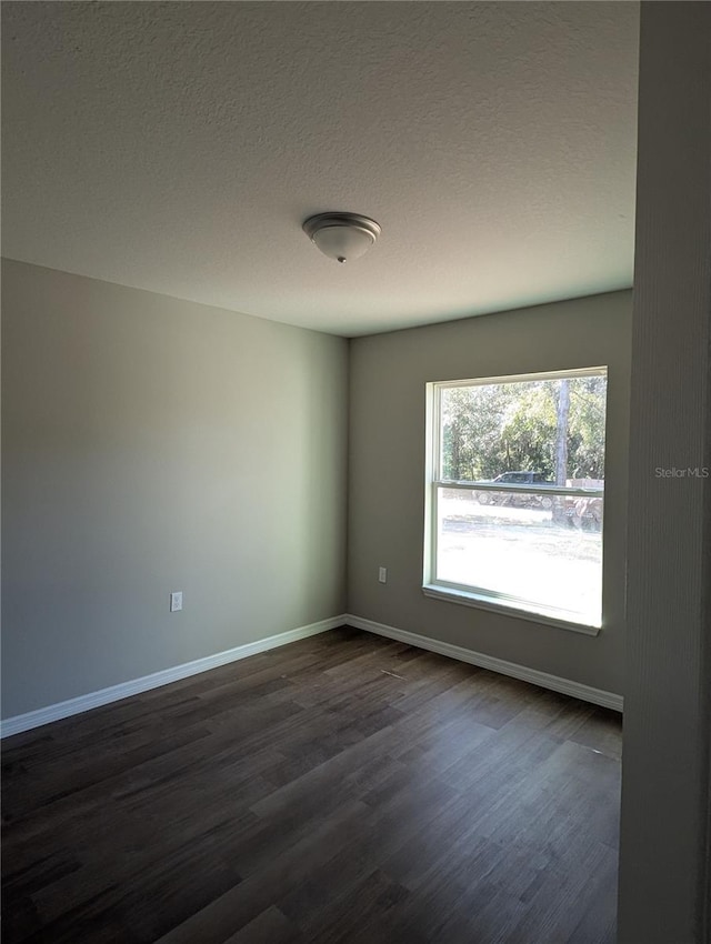 empty room with a textured ceiling and dark hardwood / wood-style floors