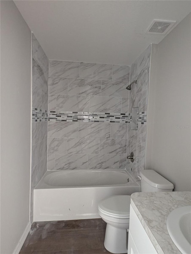 full bathroom featuring toilet, tiled shower / bath combo, wood-type flooring, and vanity