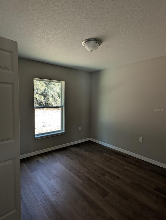 unfurnished room with dark hardwood / wood-style flooring and a textured ceiling