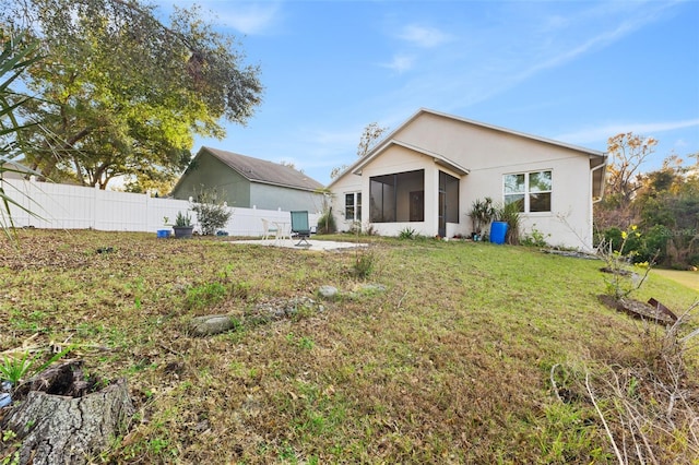 rear view of house with a yard and a sunroom