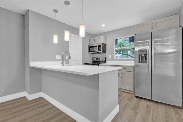 kitchen with decorative light fixtures, white cabinetry, stainless steel appliances, sink, and kitchen peninsula