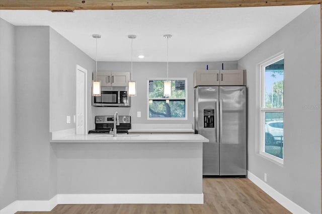 kitchen featuring a healthy amount of sunlight, kitchen peninsula, appliances with stainless steel finishes, and pendant lighting