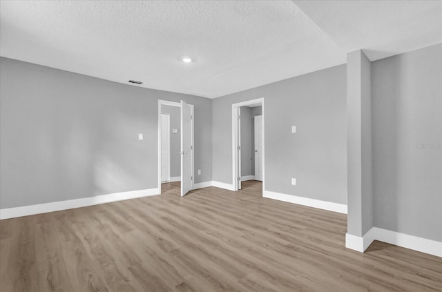 spare room featuring a textured ceiling and light hardwood / wood-style flooring