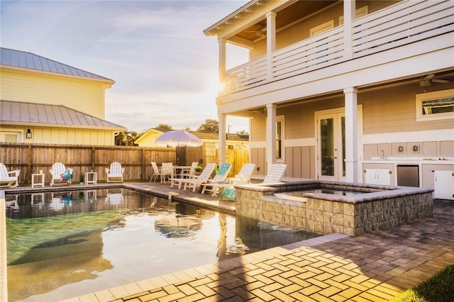 view of patio / terrace with a swimming pool with hot tub, exterior kitchen, and a balcony