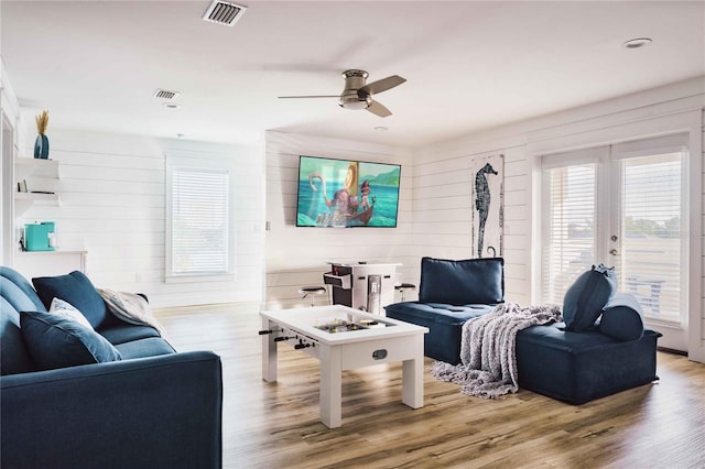 living room featuring french doors, ceiling fan, and light wood-type flooring