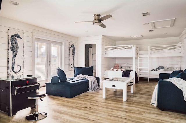 bedroom featuring ceiling fan, wood-type flooring, and wooden walls