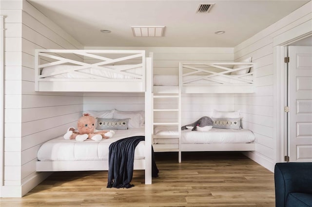 bedroom featuring hardwood / wood-style floors and wood walls