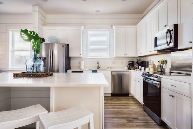 kitchen with stainless steel appliances, a center island, white cabinets, and a kitchen bar