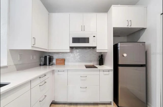 kitchen featuring white cabinets, backsplash, and stainless steel fridge