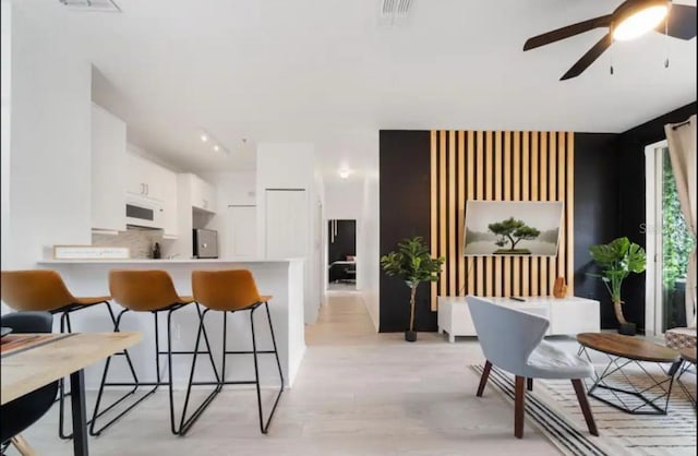 kitchen with white cabinetry, decorative backsplash, a kitchen breakfast bar, kitchen peninsula, and ceiling fan